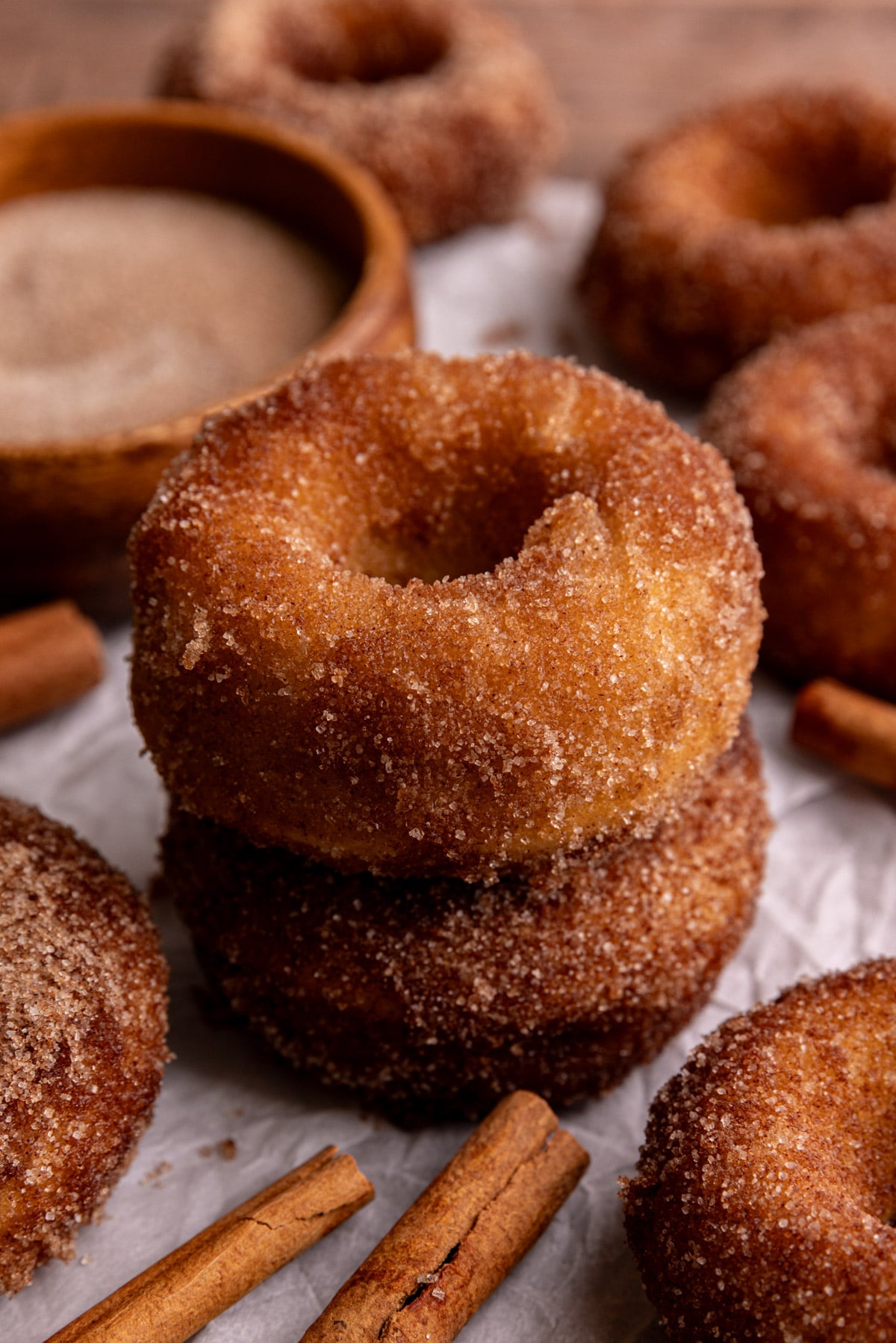 A few vegan cinnamon sugar cake donuts on a piece of parchment paper.