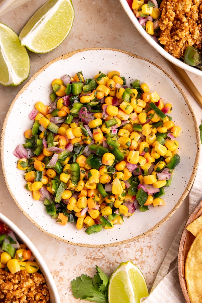 A bowl of Homemade chili corn salsa, next to two chipotle bowls.