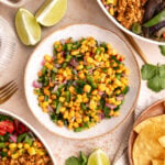 A bowl of Homemade chili corn salsa, next to two chipotle bowls.