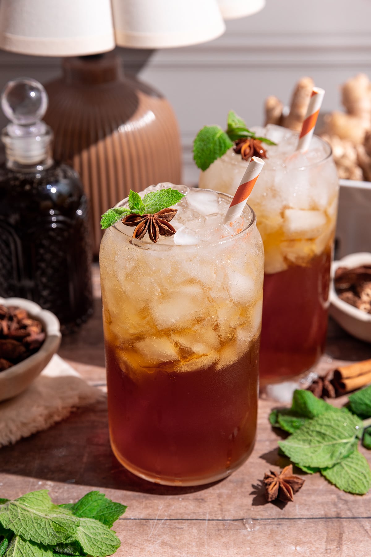 A glass of homemade root beer, garnished with a sprig of mint and a star anise.