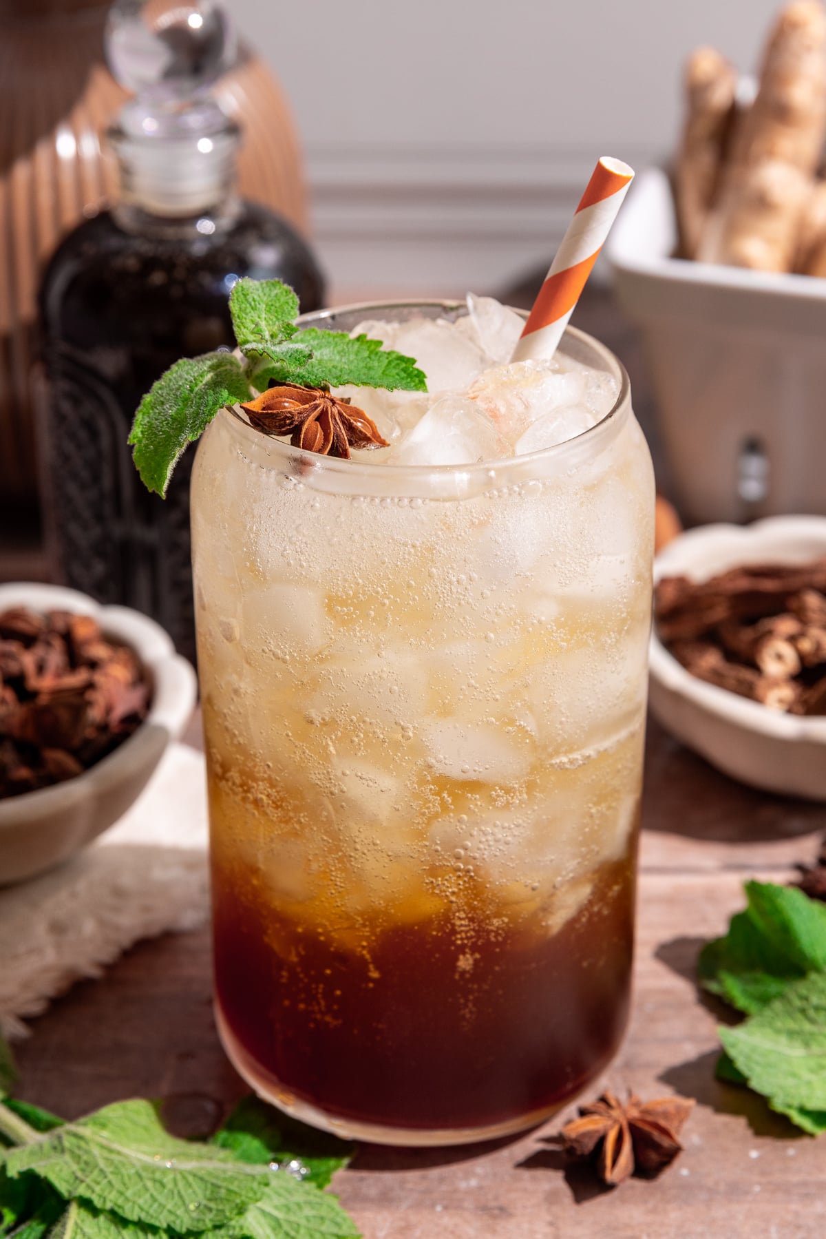 A glass of homemade root beer, garnished with a sprig of mint and a star anise.