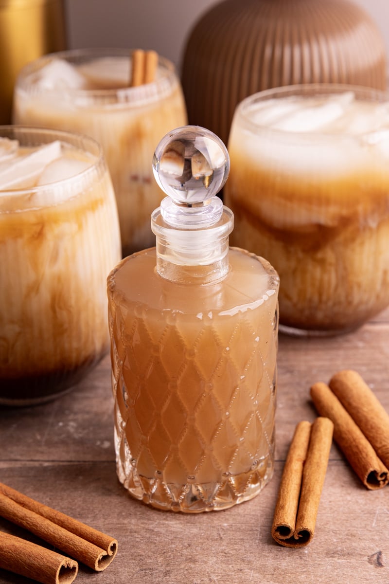 A bottle of horchata syrup, next to a few horchata shaken espresso drinks.