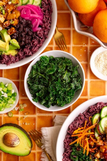 A bowl of bibibop style honey citrus kale, with two bibibop-style bowls.