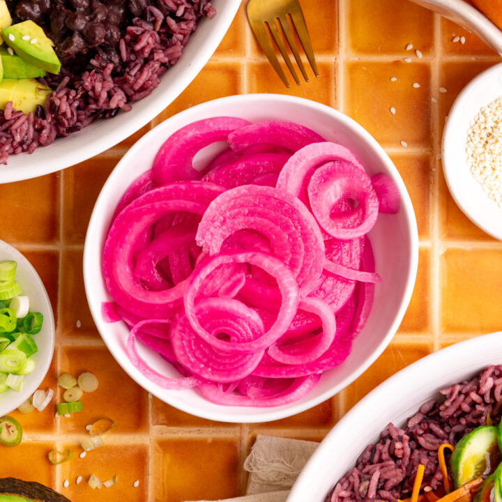 A bowl of pickled red onions, with two bibibop-style bowls.