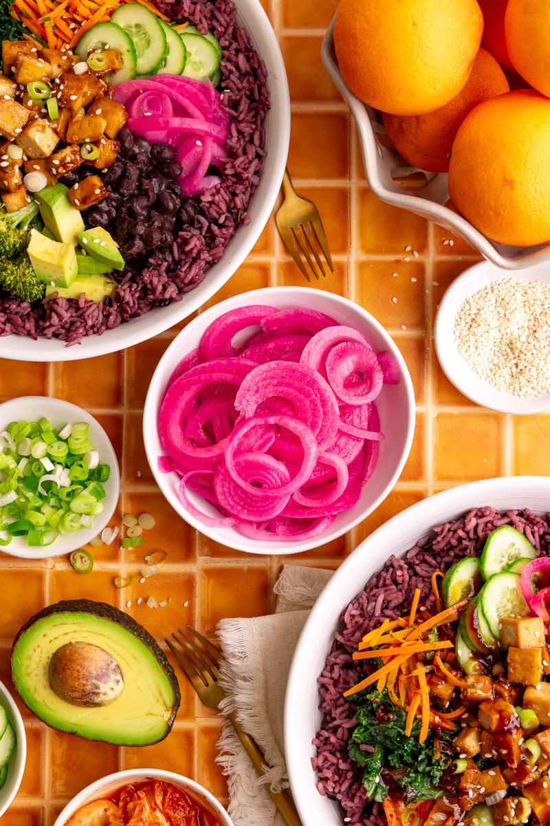 A bowl of pickled red onions, with two bibibop-style bowls.
