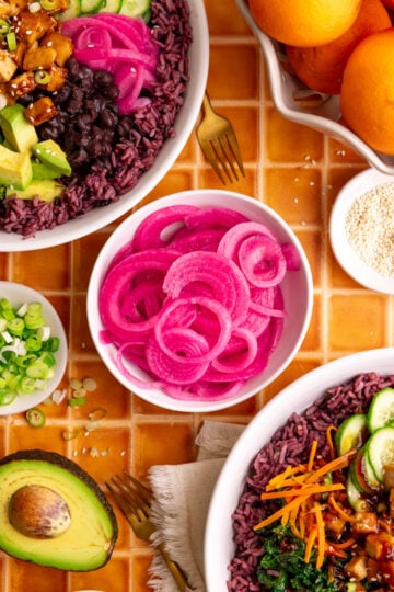 A bowl of pickled red onions, with two bibibop-style bowls.