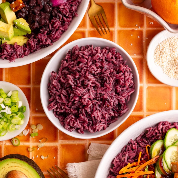 A bowl of homemade purple rice, next to two bibibop-style bowls.