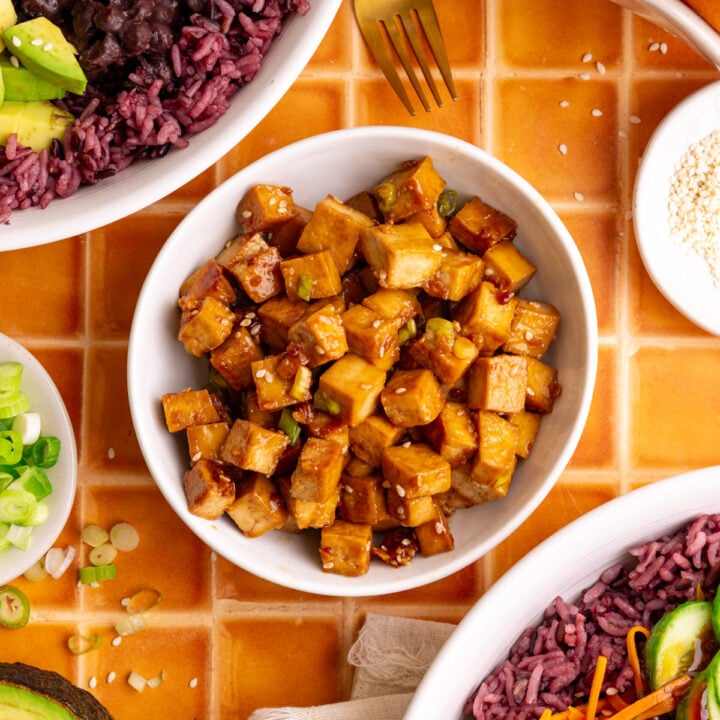 A bowl of freshly cooked tofu, next to two bibibop-style bowls.