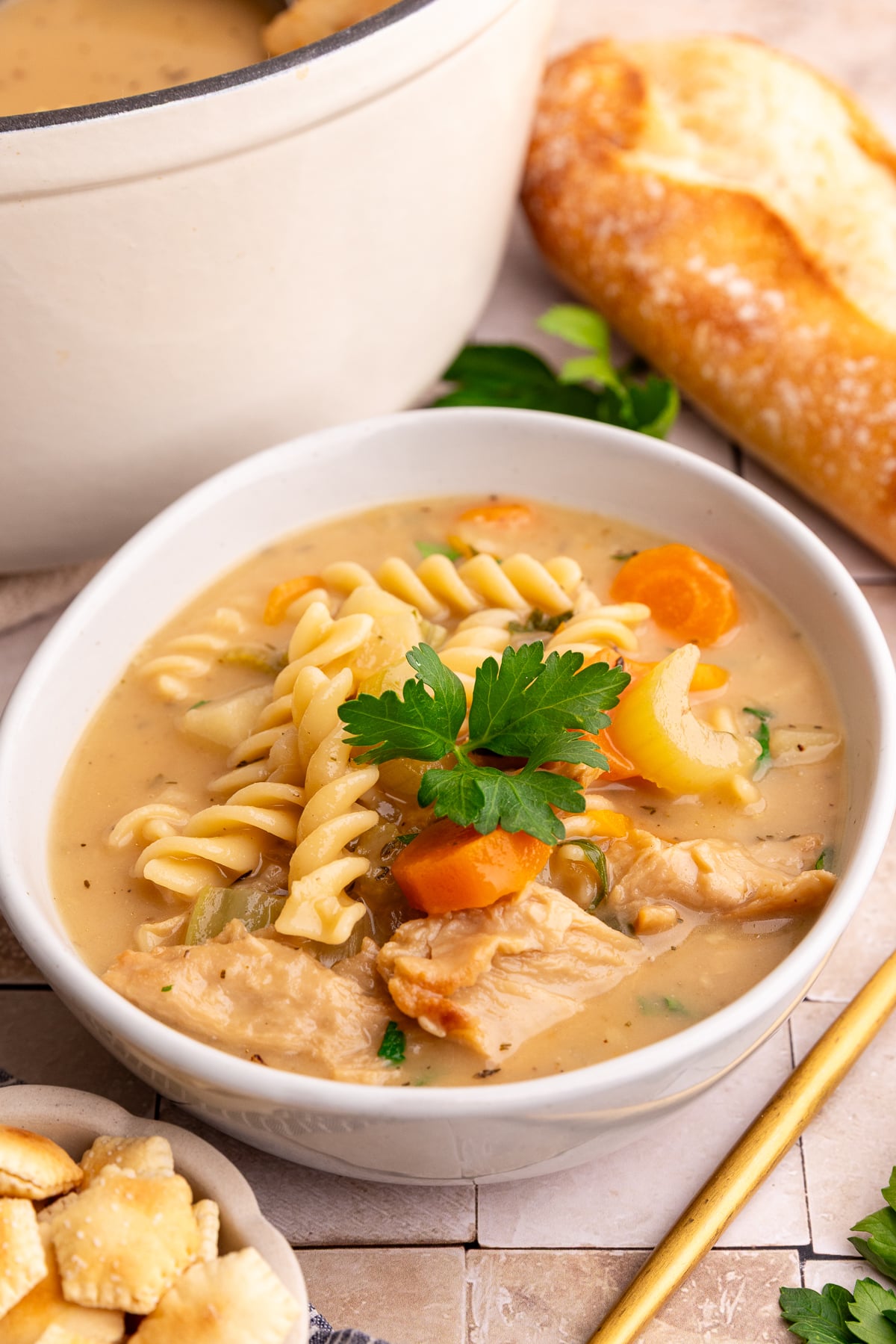 A bowl of vegan creamy chicken noodle soup, garnished with parsley.