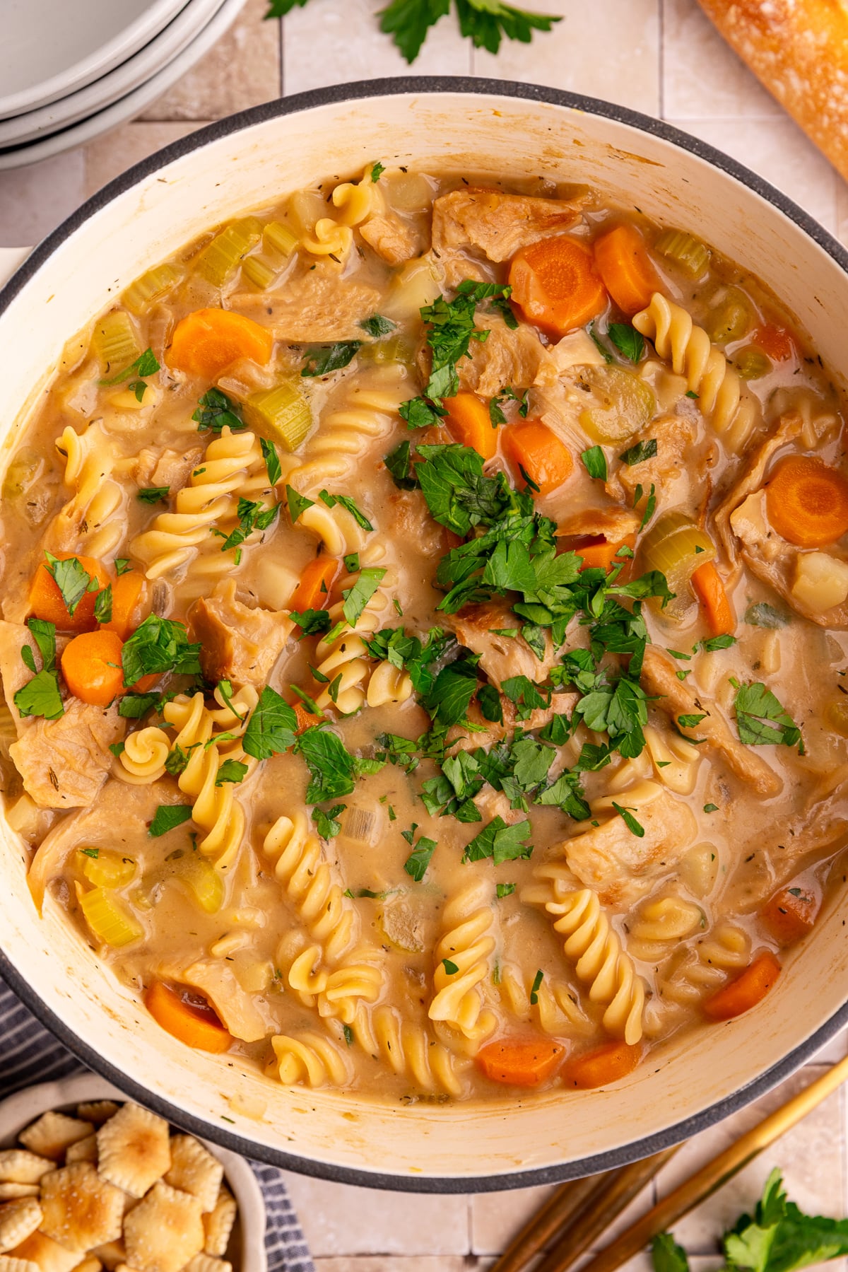 A pot of freshly cooked vegan creamy chicken noodle soup, with a sprinkle of fresh parsley.